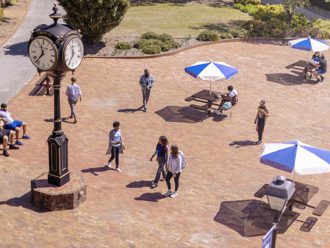 A group of people walking in the Thomas Hall plaza near the Chowan Clock.