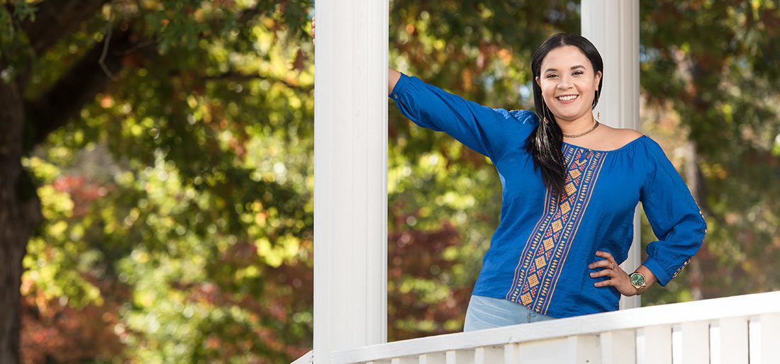 A female students stands in the Gazebo, wearing Chowan blue.
