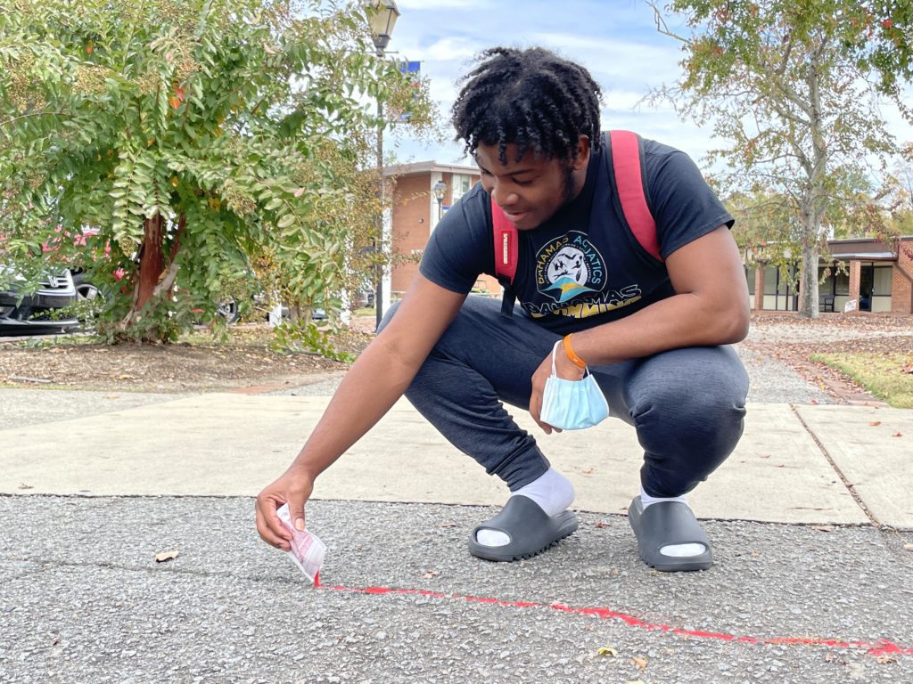 Ethan Moxey putting Red Sand in sidewalk crack