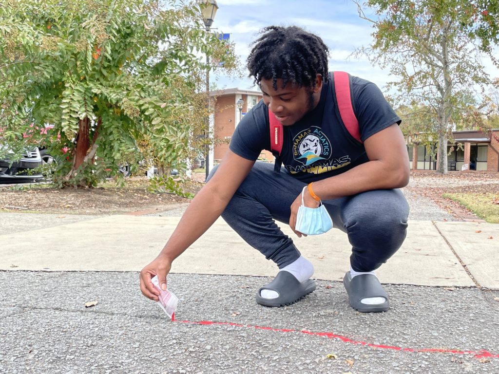 Ethan Moxey putting Red Sand in sidewalk crack