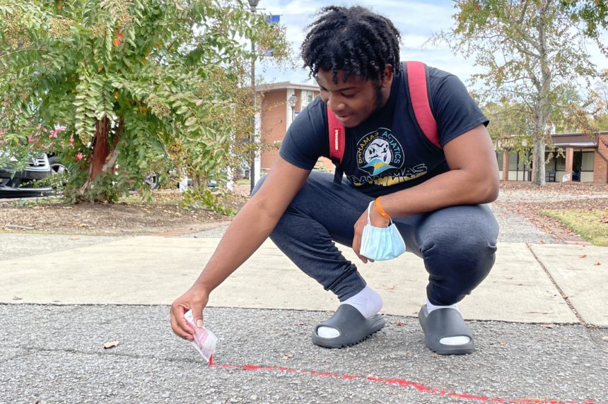 Ethan Moxey putting Red Sand in sidewalk crack