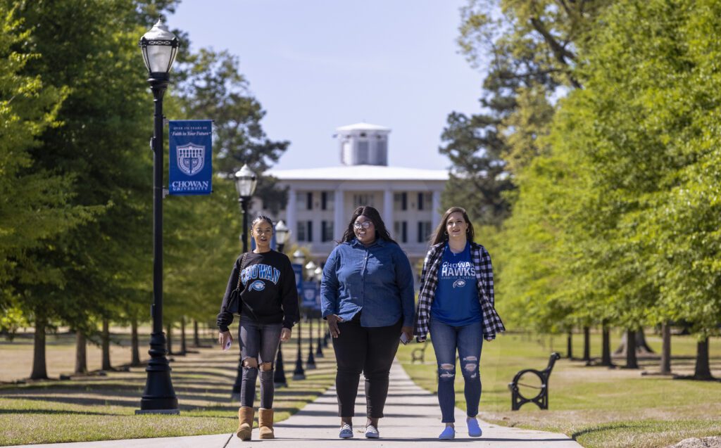 Students walk across campus in front of the Column's Building