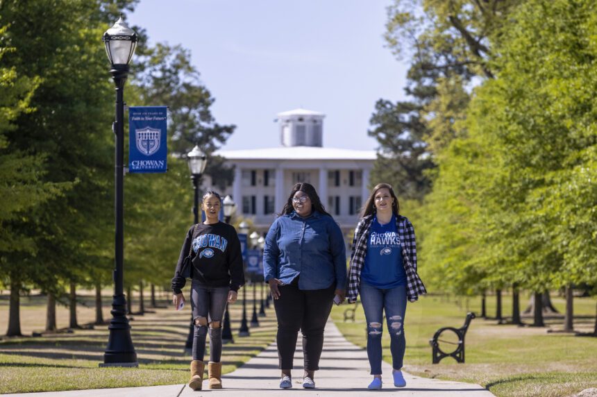 Students walk across campus in front of the Column's Building