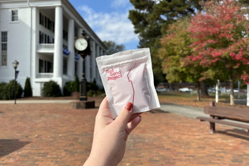 Hand holding a bad of sand for the Red Sand Project