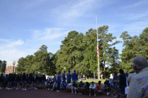 Faculty, staff and students turn to the flag as it is put at half mast to honor those who were lost.